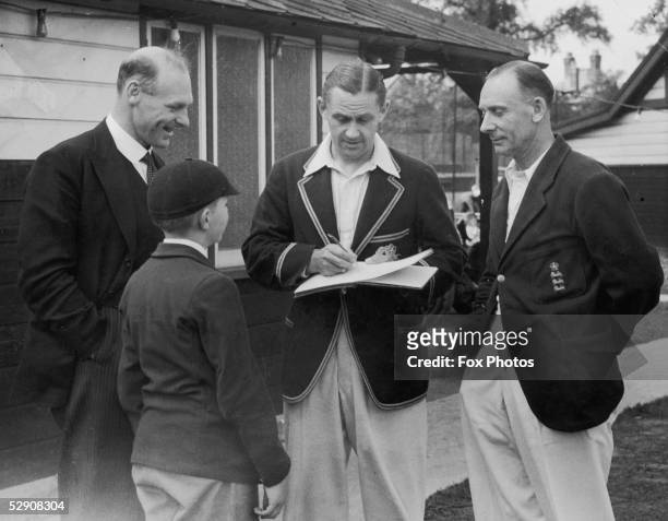 Middlesex and England bowler Gubby Allen , George Oswald Browning Allen, signing an autograph for a young fan. He is with fellow cricketer Jack Hobbs...
