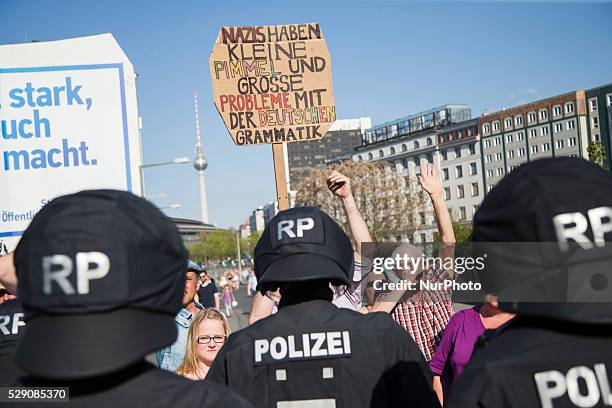 Protester holds a banner reading 'Nazis have small penises and big problems with the German grammar' while right-wing activists and Neo-Nazis march...