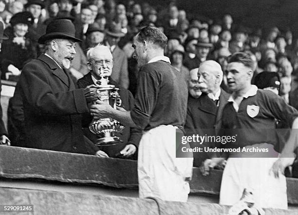 King George of England presents the Football Association trophy to Mr Parker, the captain of the Arsenals which won the Cup Final championship game...