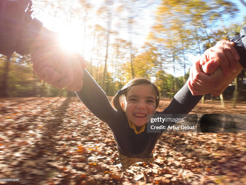 Girl spin holding hand to dad on POV autumn view.
