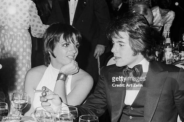 Desi Arnaz, Jr., Liza Minnelli at a black tie event sitting at their table; circa 1970; New York.