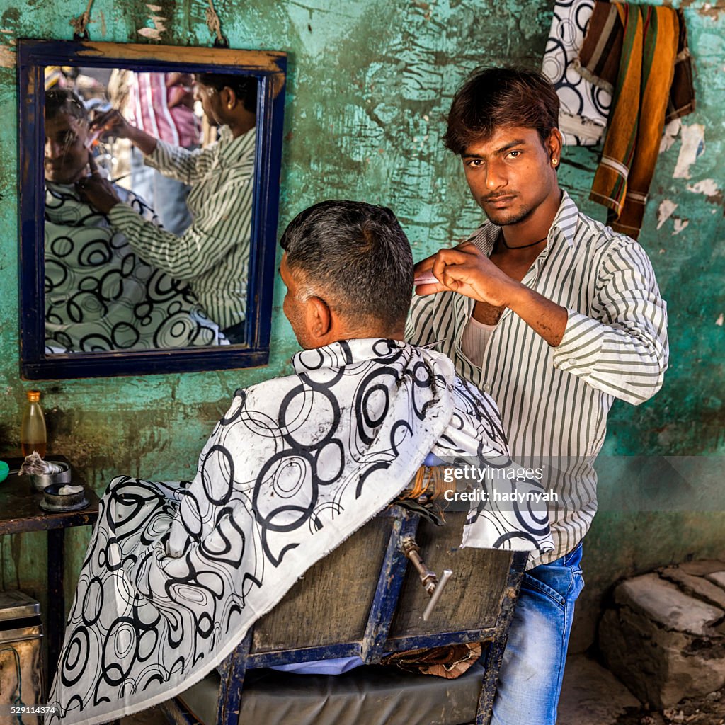 Hairdresser cutting man's hair on the streets of Jaipur, Rajasthan