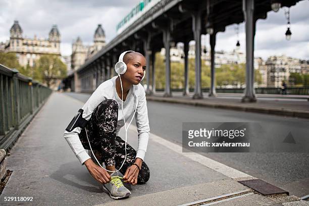 mid adult woman tying the shoelaces before running in paris - paris sport stock pictures, royalty-free photos & images