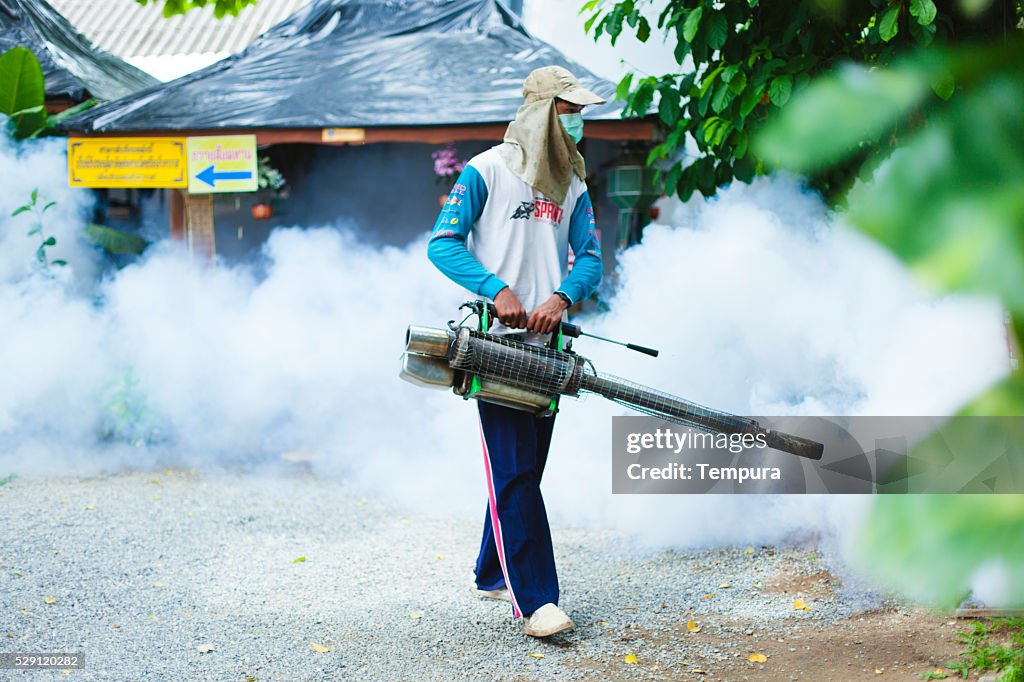 Man fogging mosquito spray in a public park