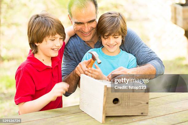 father and two sons building birdhouse outdoors. family time! - fathers day tools stock pictures, royalty-free photos & images