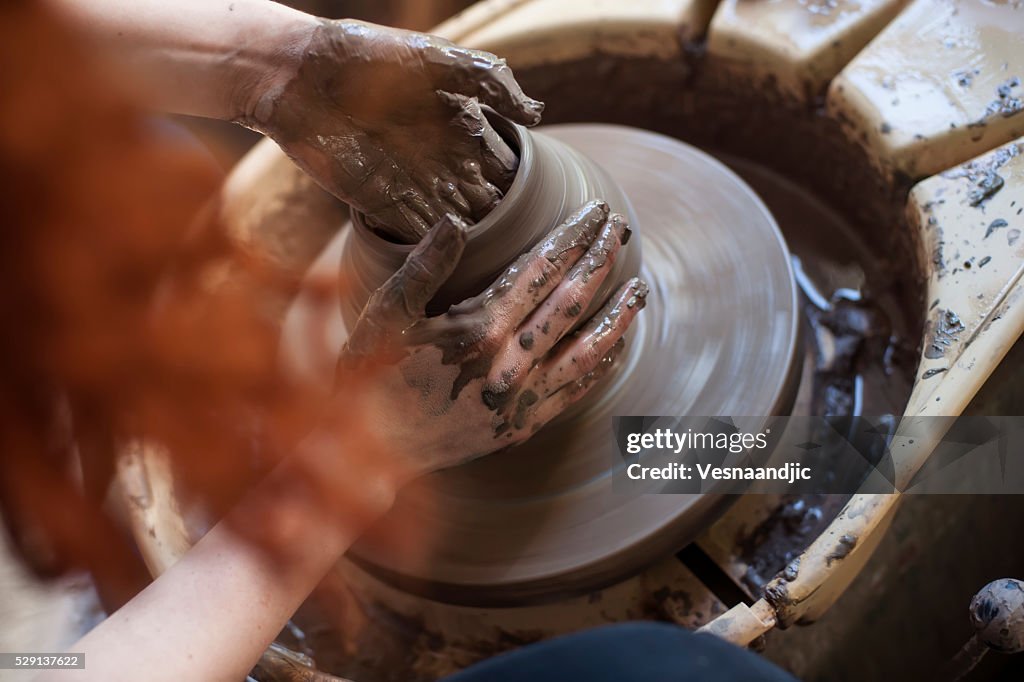 Hands working on pottery wheel