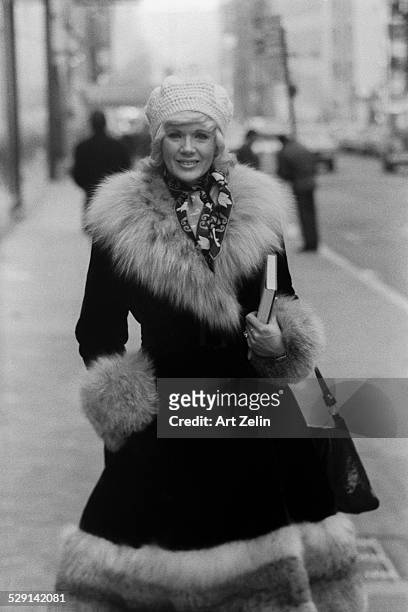 Connie Stevens wearing a fur trimmed coat walking on the street; circa 1970; New York.