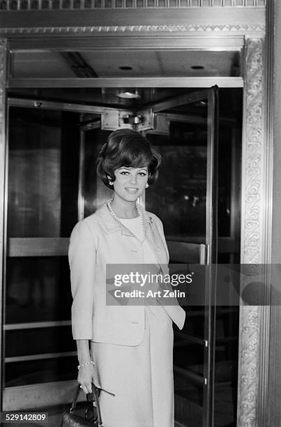 Claudia Cardinale, wearing a pants suit in front of a revolving door; circa 1970; New York.