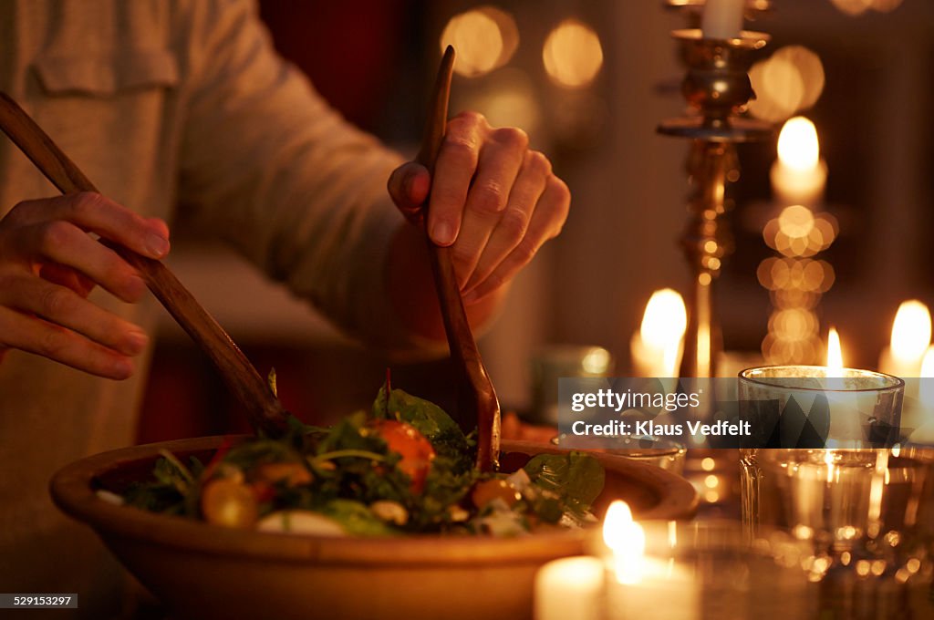 Man taking salad from bowl at candlelight dinner