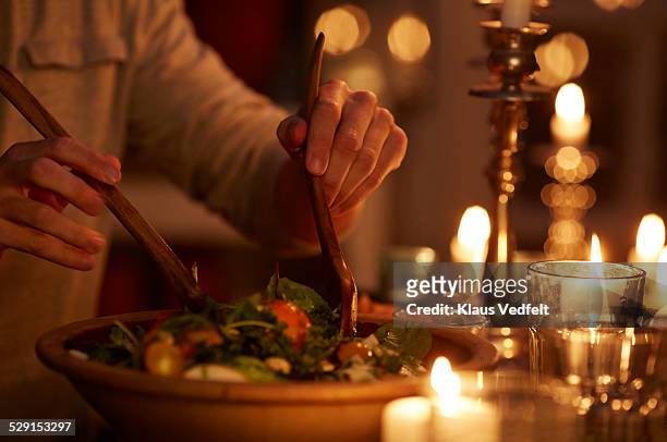 man taking salad from bowl at candlelight dinner - candle photos et images de collection
