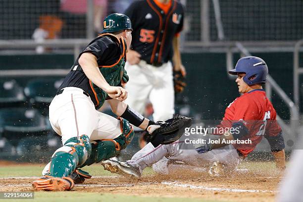 May 5: Sean Labsan of the Florida Atlantic Owls scores past the attempted tag by Zack Collins of the Miami Hurricanes during fifth inning action on...