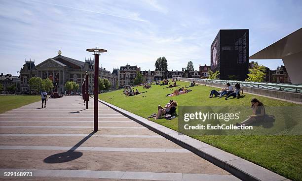 people enjoying sun at museumplein in amsterdam - museumplein stockfoto's en -beelden