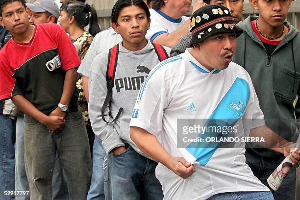 Un aficionado de la seleccion de futbol de Guatemala muestra la camiseta de su pais el 18 de mayo de 2005, mientras se dispone a comprar su boleto en...