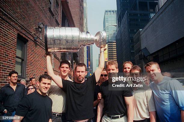 The New Jersey Devil's Hockey Team with the Stanley Cup, 1995. MVP Claude Lemieux left of the man holding the cup. They are being interviewed on the...