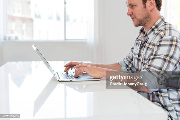 casual man using laptop at desk - johnny stark stock pictures, royalty-free photos & images