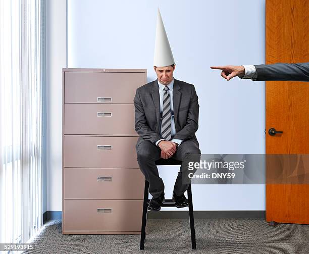 businessman with dunce cap - workplace bullying stock pictures, royalty-free photos & images