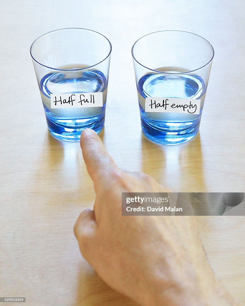 Hand pointing at half full glass