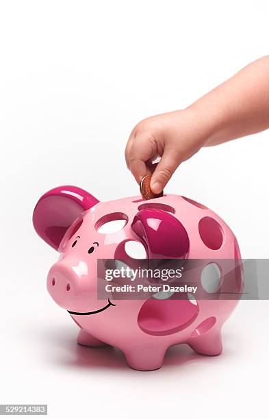 3 year old putting coin in piggy bank - pocket money uk stock pictures, royalty-free photos & images
