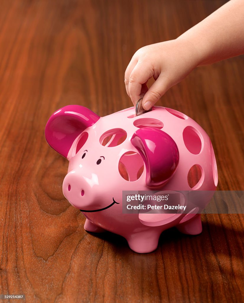 3 year old putting pocket money in piggy bank