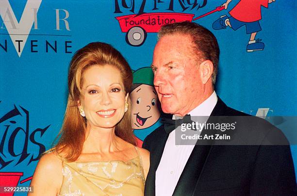 Frank Gifford with his wife Kathie Lee Gifford in front of a cartoon backdrop; circa 1990; New York.