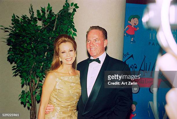 Frank Gifford with his wife Kathie Lee Gifford in front of a cartoon backdrop; circa 1990; New York.