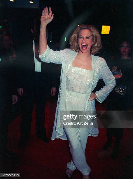 Cybill Shepherd dancing down the red carpet in a white sequined pants suit; circa 1990; New York.