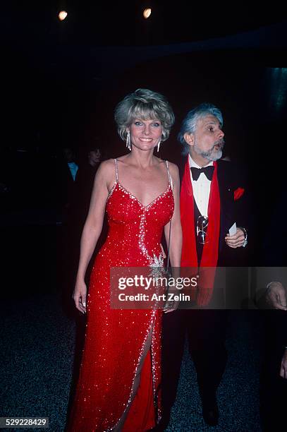 Cathy Lee Crosby wearing a red beaded gown with a friend in a tux; circa 1970; New York.