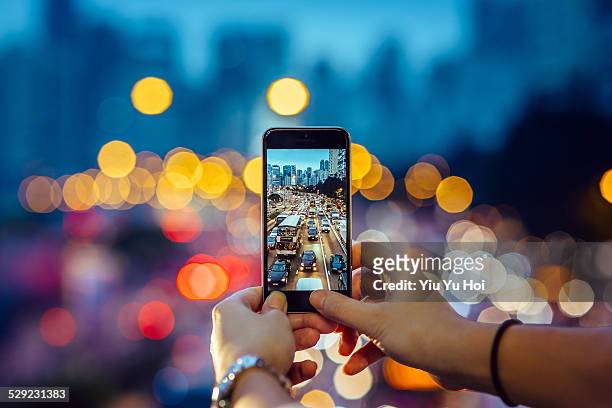 woman capturing the busy traffic with smartphone - temi per la fotografia foto e immagini stock