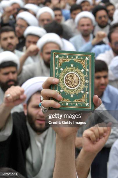 Person holds up a copy of the Quran as Iranian religious students chant during a protest at the Faizieh religious school May 18, 2005 in the clerical...