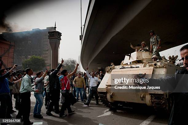 Crowds cheer on the military as they enter the square as goverment building in the background still smoulder from the "Day of Rage" After the...