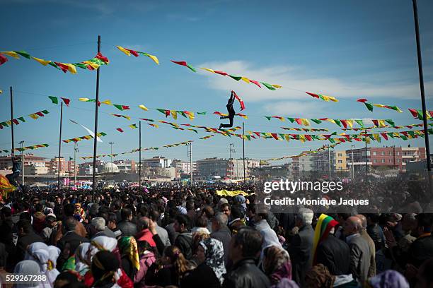 Men on trampoline hold up flags at Nowruz, an ancient holiday celebrating the astronomical Northward equinox and the beginning of spring as well as...