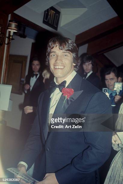 Arnold Schwarzenegger in a tux with a red carnation; circa 1970; New York.
