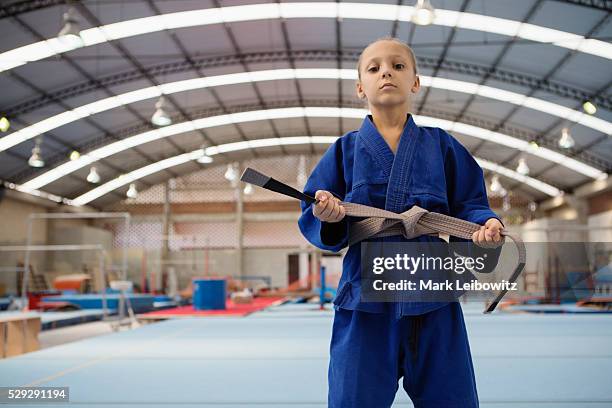 girl (8-9) wearing blue gi adjusting belt - gi abbigliamento per arti marziali foto e immagini stock