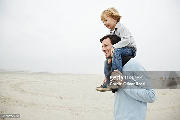 father carrying son on shoulders - on shoulders stock pictures, royalty-free photos & images
