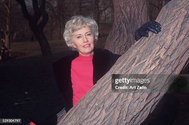 Barbara Stanwyck posing for the photo by a tree; circa 1970; New York.