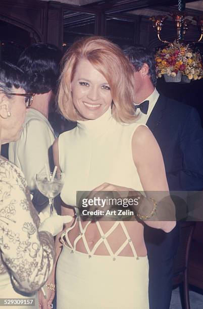 Angie Dickinson at a formal event wearing a white bare midriff dress; circa 1970; New York.