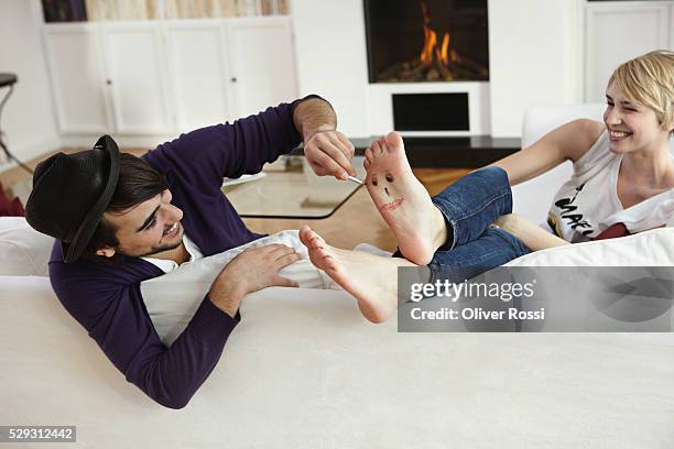 man drawing face on woman's foot - lustige füße stock-fotos und bilder