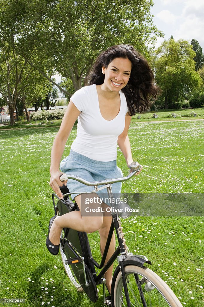 Young woman riding bicycle in grass