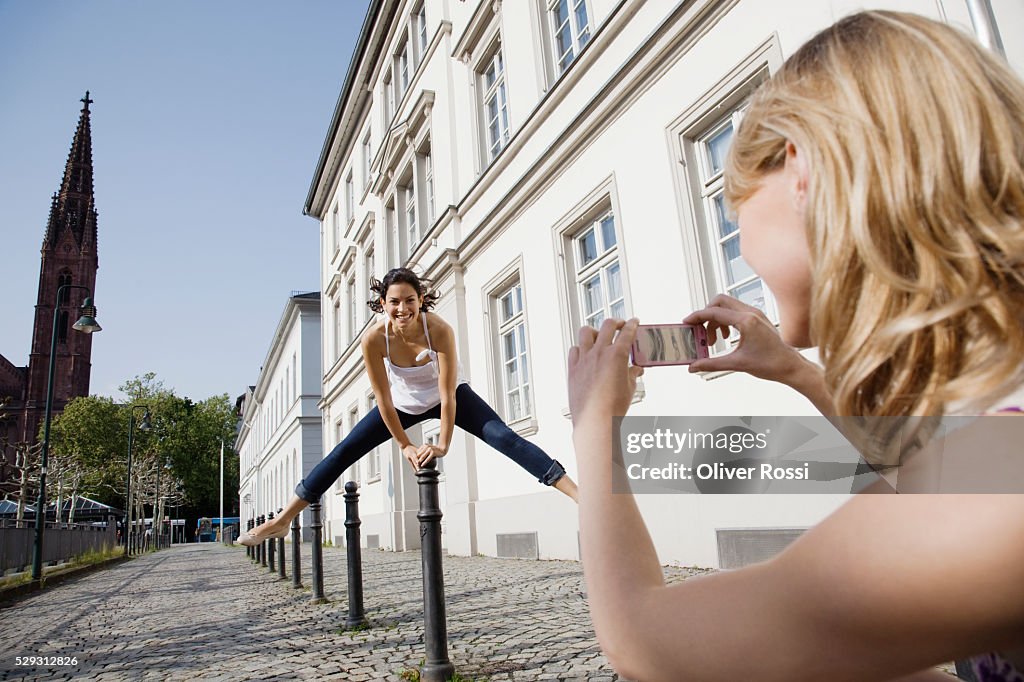 Young woman photographing friend jumping
