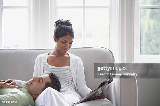 couple relaxing on couch - mixed magazine foto e immagini stock