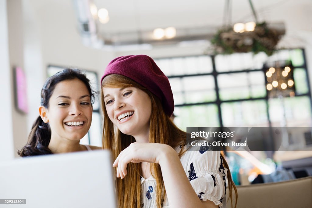 Friends using laptop in cafe