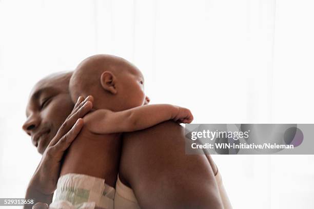 mid adult father embracing baby boy (0-1 months) - baby father hug side stock pictures, royalty-free photos & images