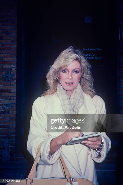 Donna Mills signing autographs. She is wearing a white coat; circa 1970; New York.