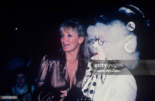 Linda Evans wearing taupe with a person dressed as a rabbit; circa 1970; New York.