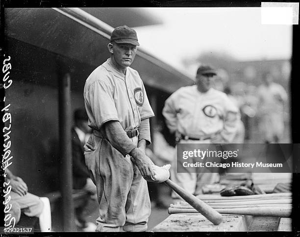 Chicago Cubs baseball player Rogers Hornsby holding a rosin bag on a baseball bat, standing in a dugout at Wrigley Field, Chicago, Illinois, 1929.