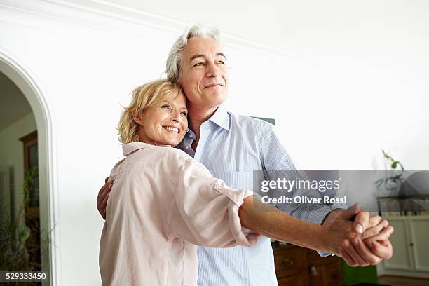 middle-aged couple dancing and smiling - couple dancing at home stockfoto's en -beelden