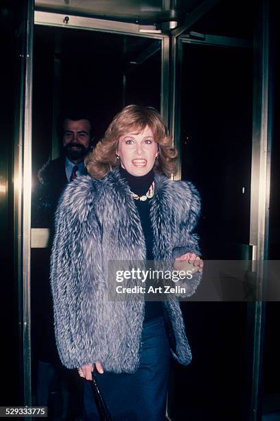 Stefanie Powers coming through a revolving door wearing a fur coat; circa 1970; New York.