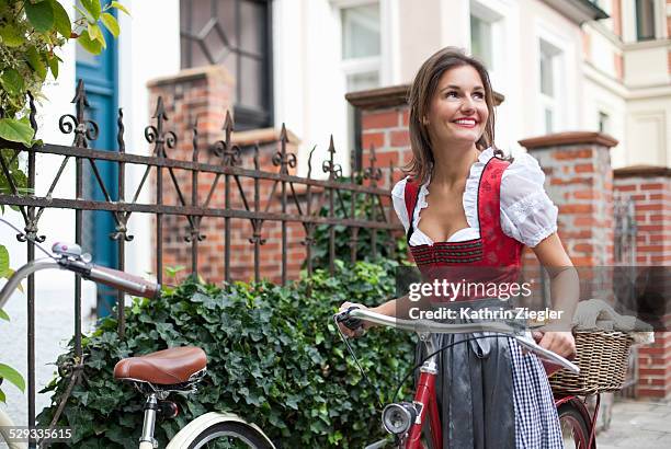 woman with bicycle, wearing dirndl dress - identidades culturales fotografías e imágenes de stock