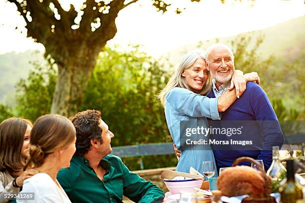family with loving couple having meal in yard - candid mature couple outdoors stock-fotos und bilder