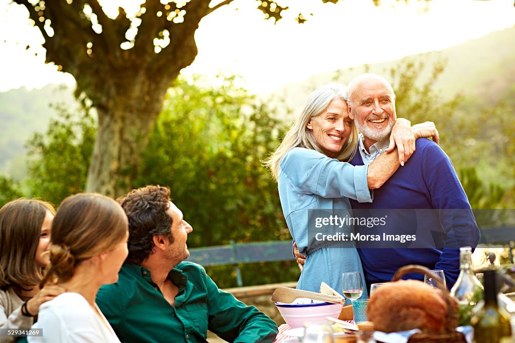 Family with loving couple having meal in yard